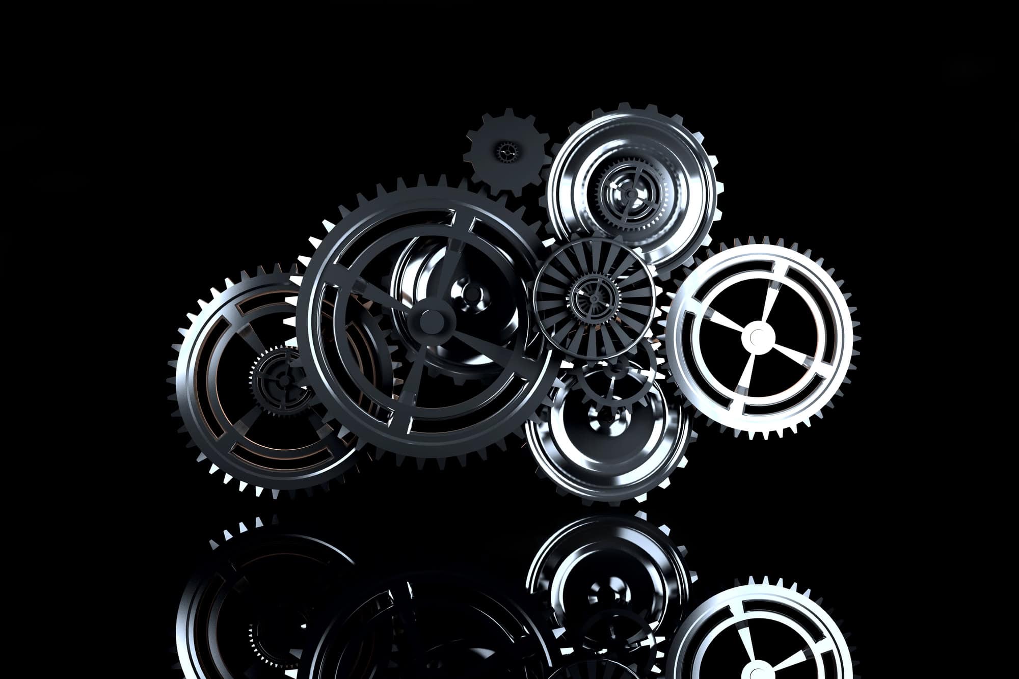 A group of interlocking metallic gears displayed against a black reflective background.