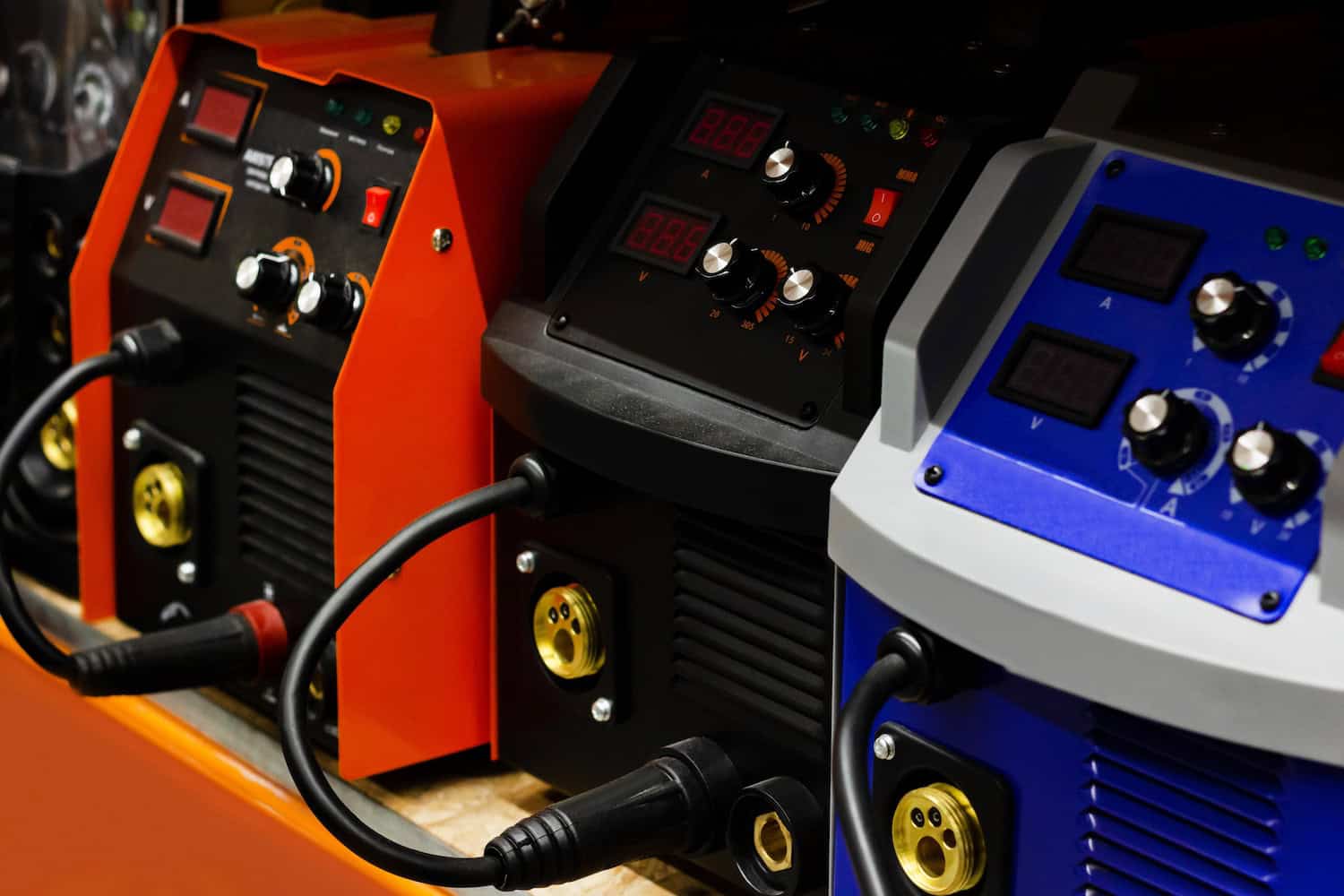 Three welding machines with control panels and cables, shown in red, black, and blue colors.