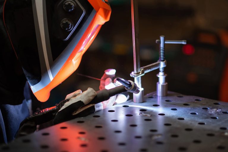 Welder using clamps to hold metal in place on a fixture table before welding.